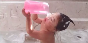 Baby Rosie pouring water over face in bathtub
